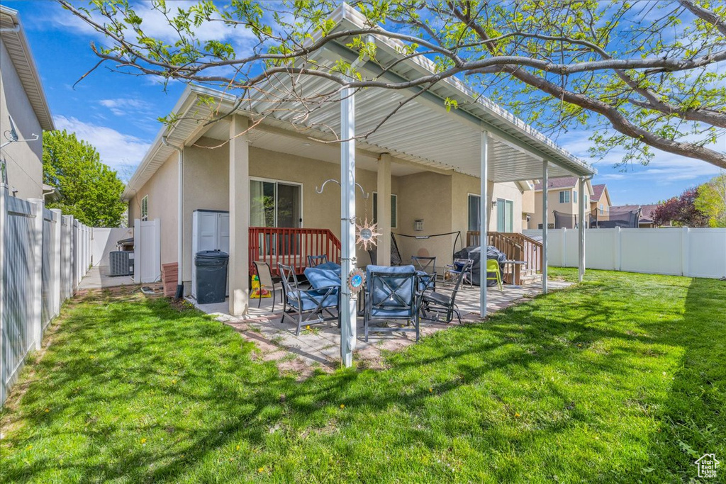 Back of house featuring a fenced backyard, stucco siding, a patio, cooling unit, and a lawn