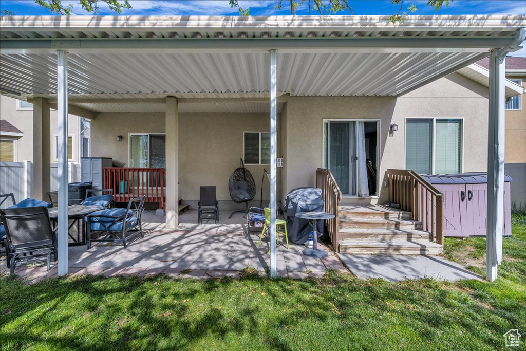 Back of house featuring a lawn, stucco siding, and a patio area