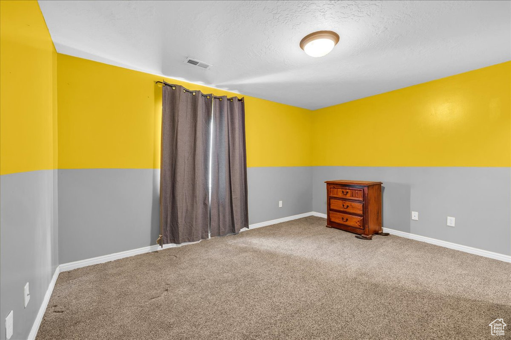 Unfurnished room featuring baseboards, visible vents, carpet floors, and a textured ceiling
