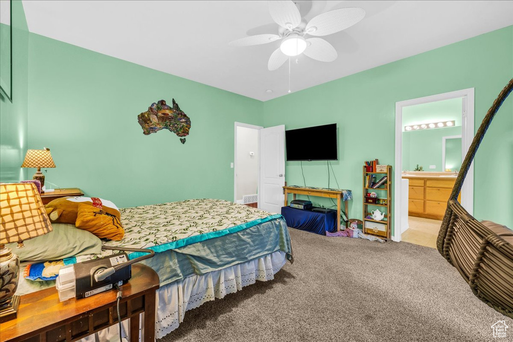 Carpeted bedroom featuring ceiling fan and ensuite bath