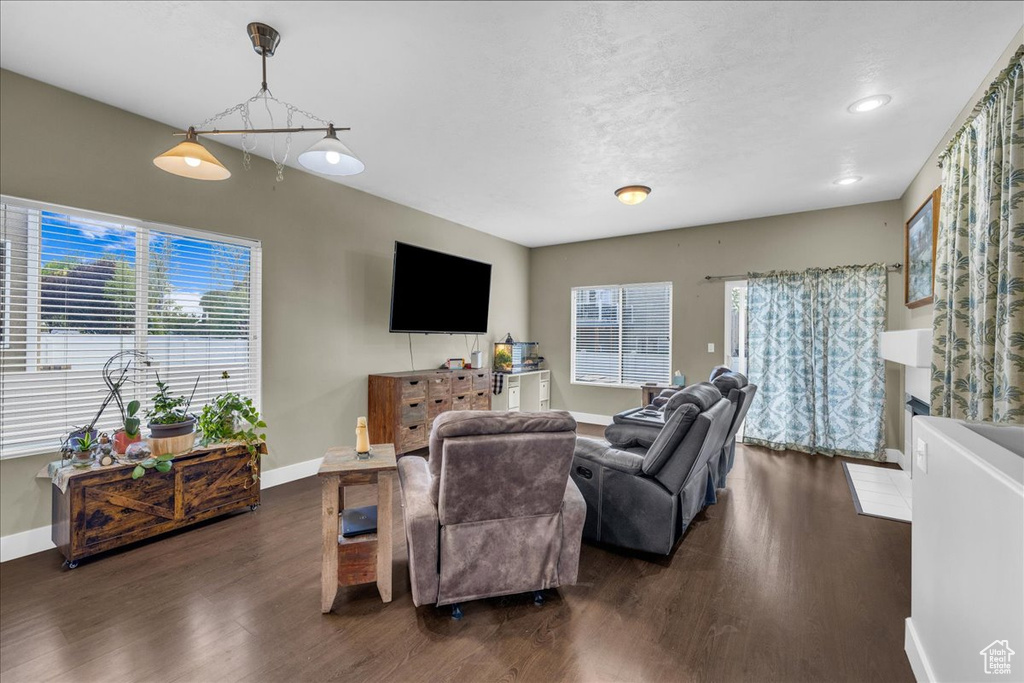 Living room featuring dark wood-style floors, baseboards, and a wealth of natural light