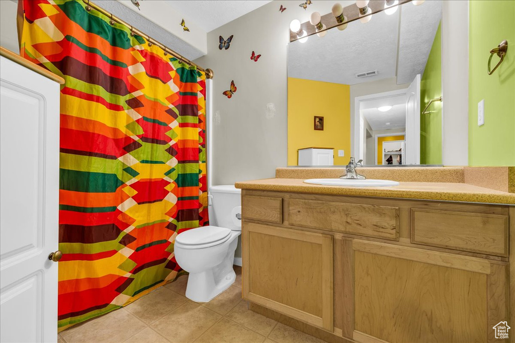 Bathroom with a shower with curtain, visible vents, toilet, vanity, and tile patterned flooring