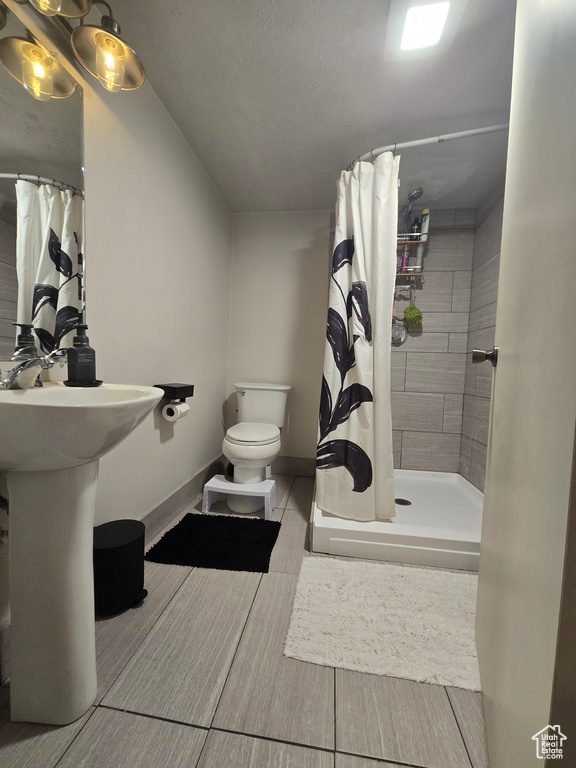Bathroom with baseboards, a shower stall, and toilet