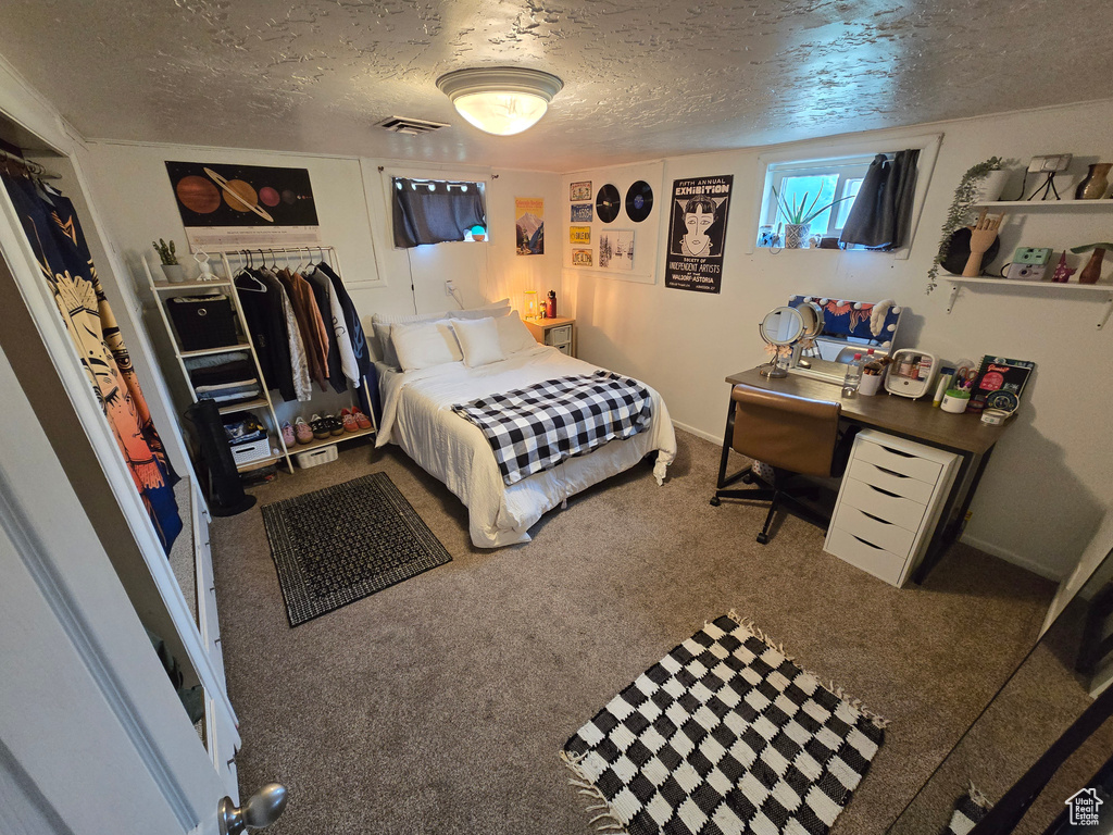 Bedroom featuring visible vents, a textured ceiling, and carpet