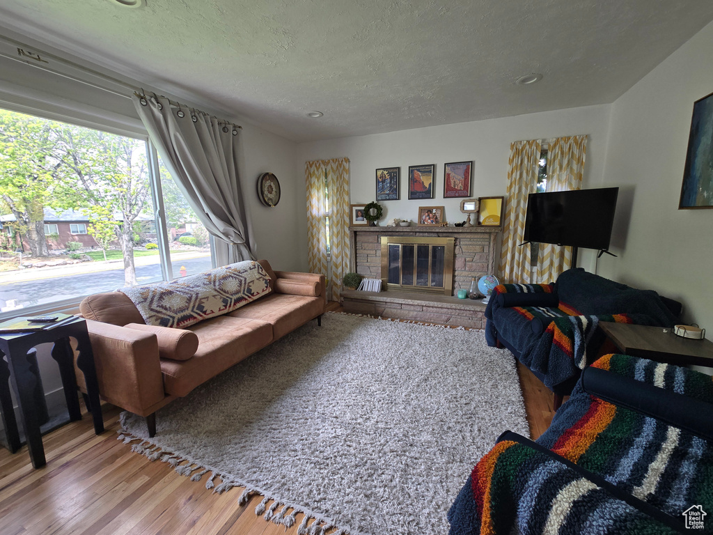 Living area with a fireplace, a textured ceiling, and wood finished floors
