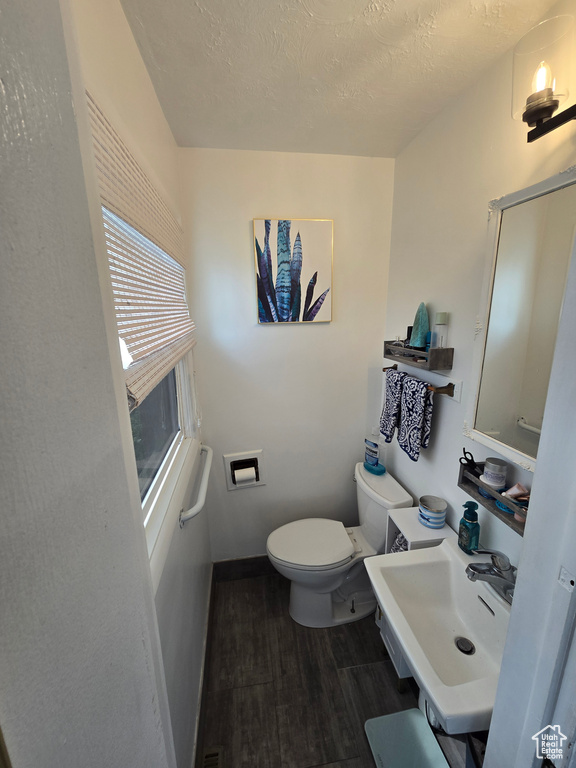Bathroom featuring a sink, toilet, baseboards, a textured ceiling, and wood finished floors