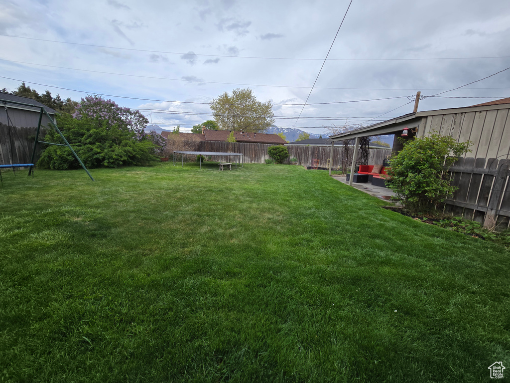 View of yard featuring a trampoline and a fenced backyard