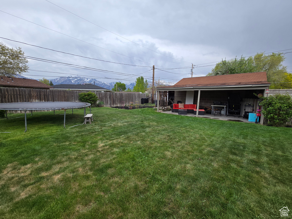 View of yard with outdoor lounge area, a trampoline, a patio area, and fence