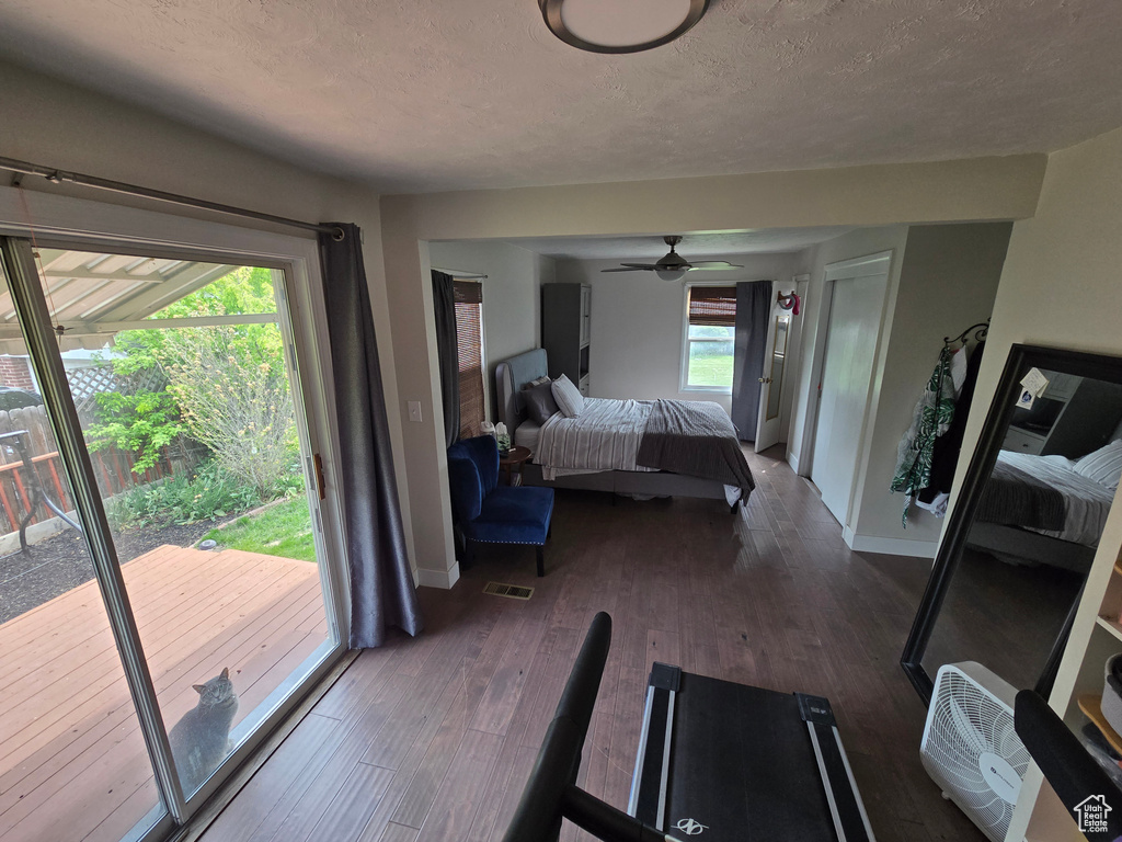 Bedroom featuring wood finished floors, access to exterior, baseboards, visible vents, and a textured ceiling