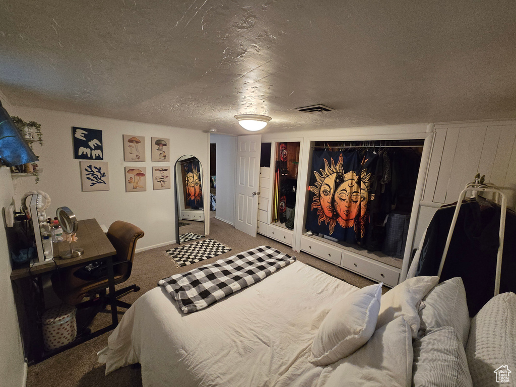 Bedroom with a textured ceiling, visible vents, baseboards, carpet floors, and multiple closets