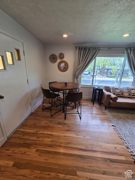 Dining space with baseboards, recessed lighting, wood finished floors, and a textured ceiling