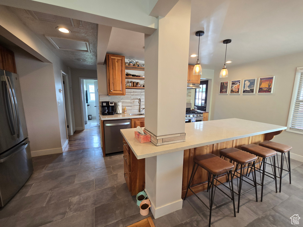 Kitchen with a sink, a breakfast bar area, stainless steel appliances, and baseboards