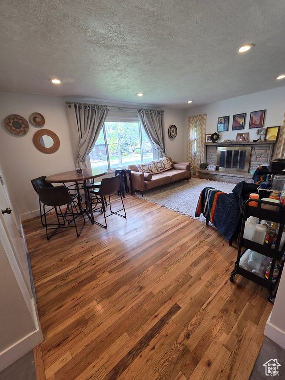 Living room with wood-type flooring, recessed lighting, a textured ceiling, and baseboards