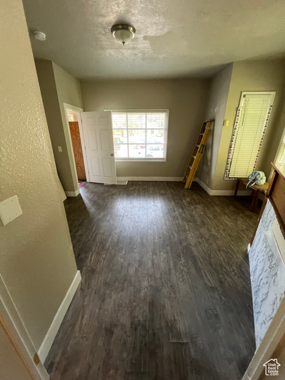 Interior space with a textured ceiling, dark wood finished floors, and baseboards