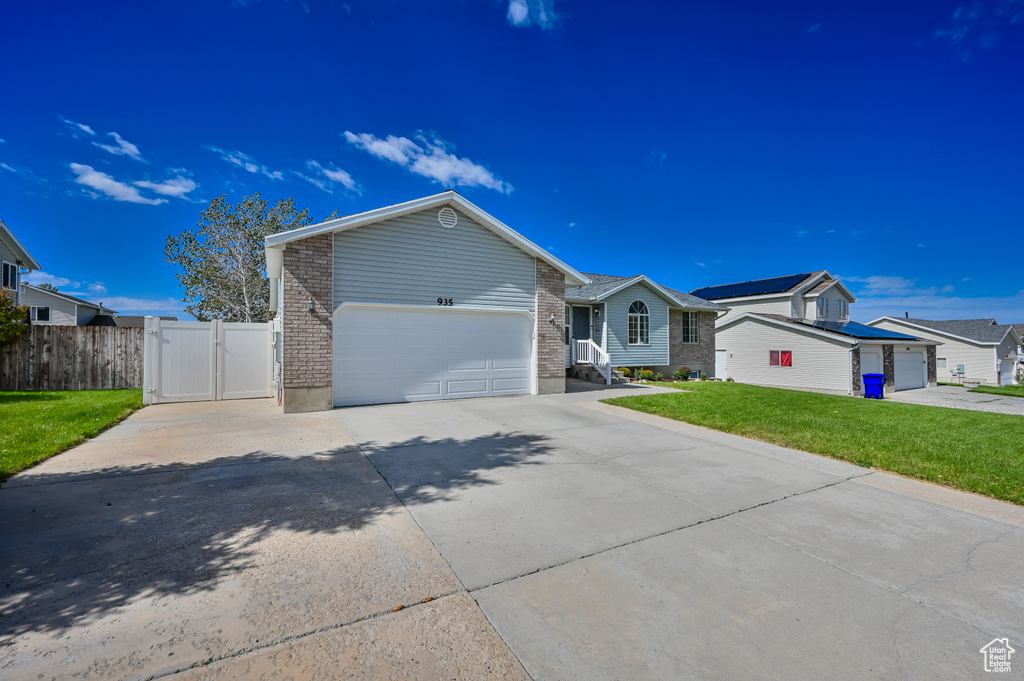 Single story home featuring a front lawn, a garage, a gate, concrete driveway, and fence