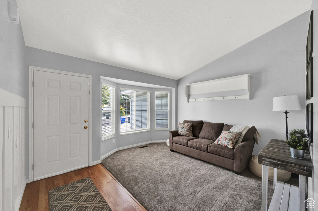 Living room featuring baseboards, visible vents, wood finished floors, and lofted ceiling