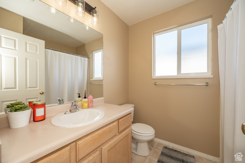Bathroom featuring toilet, tile patterned floors, vanity, and baseboards