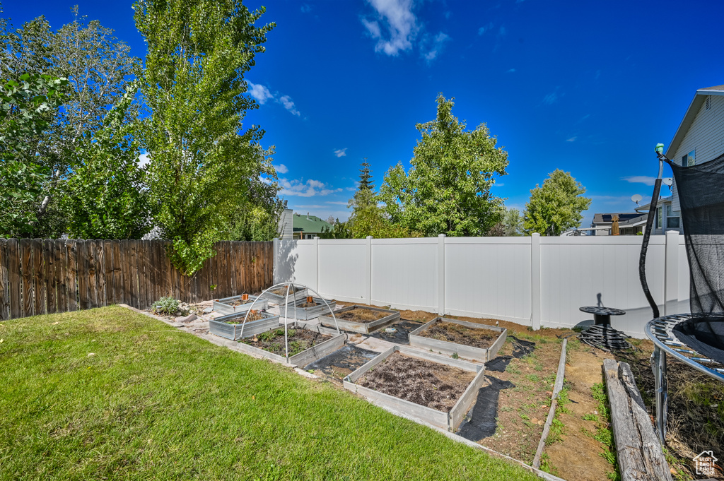 View of yard with a fenced backyard, a vegetable garden, and a trampoline