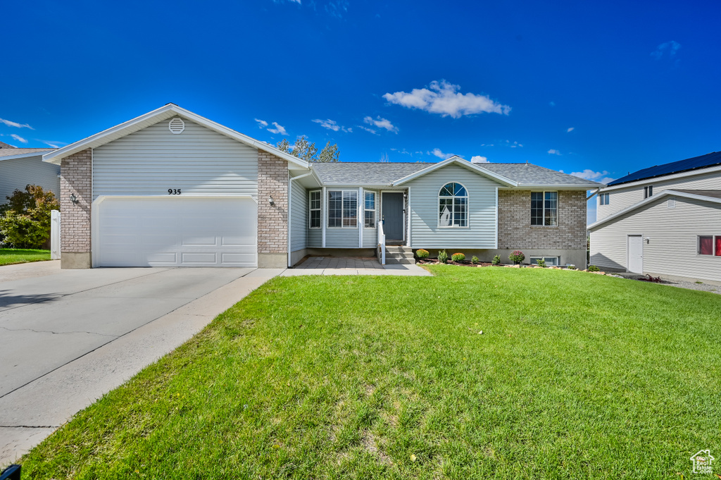 Ranch-style home with brick siding, a front lawn, driveway, and an attached garage