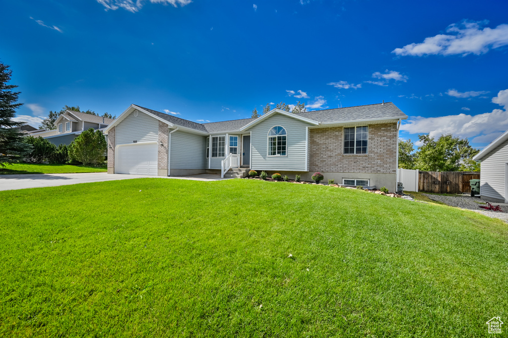 Single story home featuring fence, a front yard, an attached garage, and brick siding
