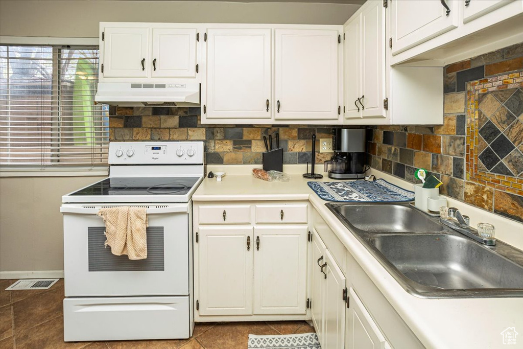 Kitchen with white cabinetry, white electric range, under cabinet range hood, and a sink