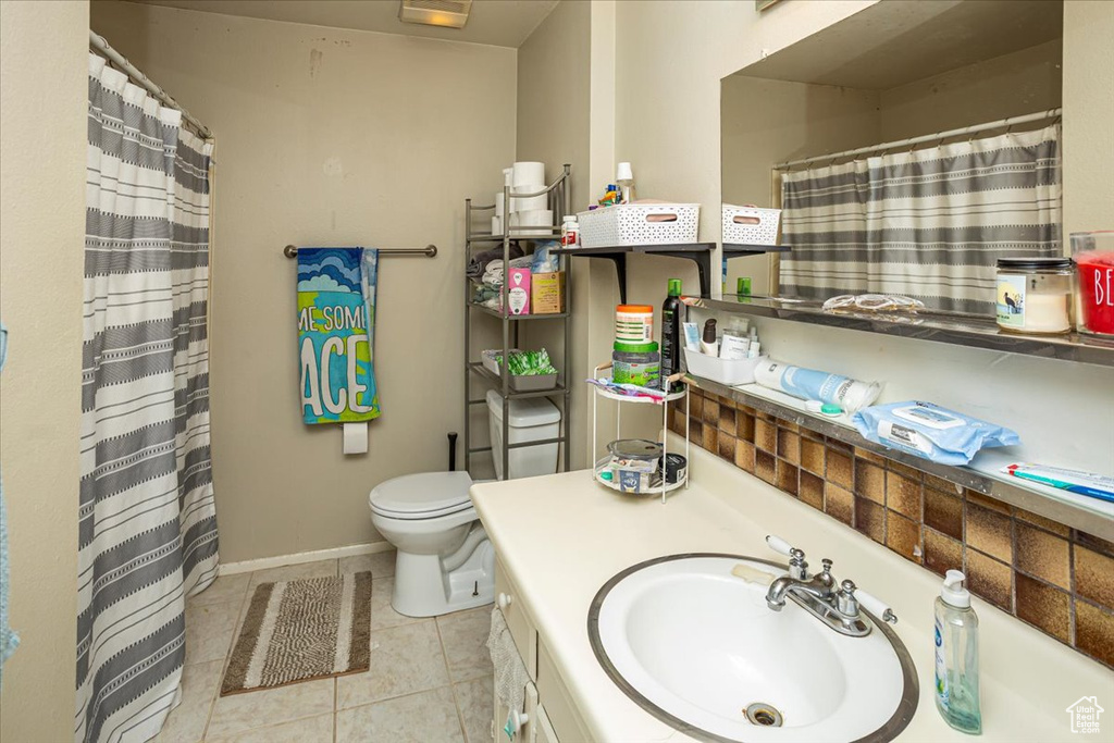 Bathroom featuring vanity, toilet, baseboards, tile patterned flooring, and a shower with shower curtain