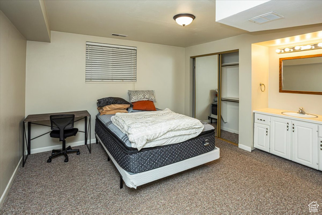 Bedroom featuring dark carpet, a sink, visible vents, a closet, and baseboards