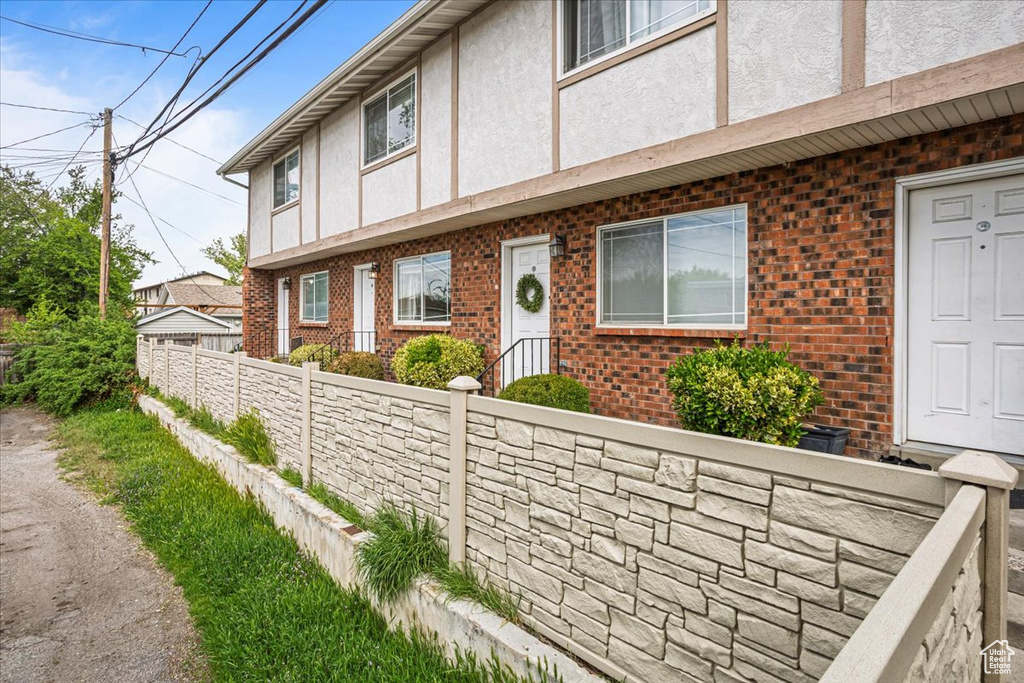 View of front facade with brick siding, fence, and stucco siding