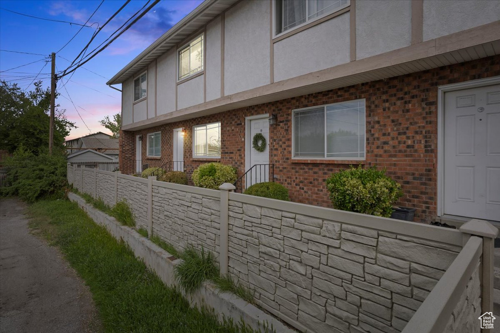 View of front of property featuring brick siding, fence, and stucco siding
