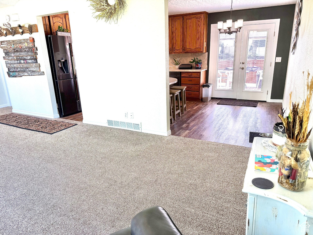 Kitchen with fridge with ice dispenser, brown cabinets, a chandelier, light countertops, and baseboards