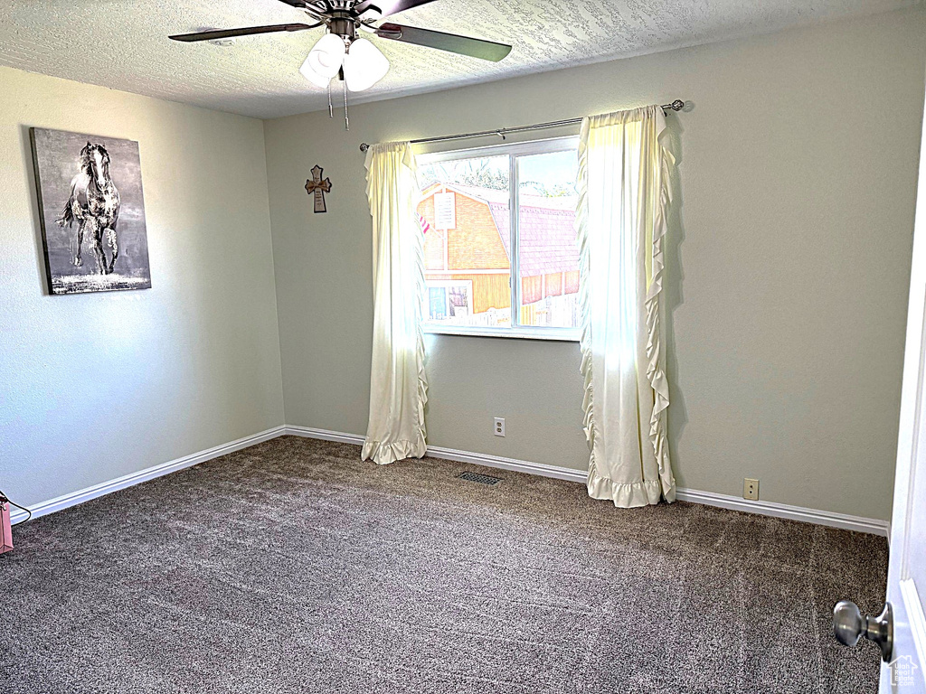 Spare room featuring ceiling fan, carpet flooring, a textured ceiling, and baseboards