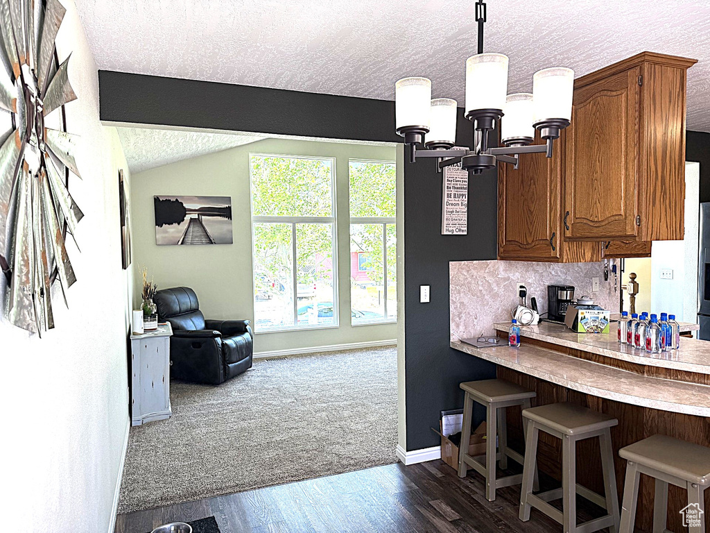 Kitchen with a chandelier, baseboards, a textured ceiling, brown cabinetry, and light countertops