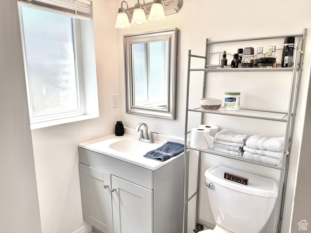 Half bath featuring vanity, toilet, and a chandelier