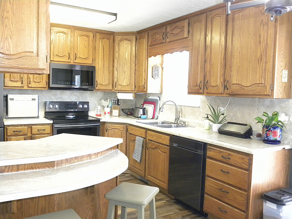 Kitchen featuring stainless steel appliances, a sink, light countertops, and backsplash