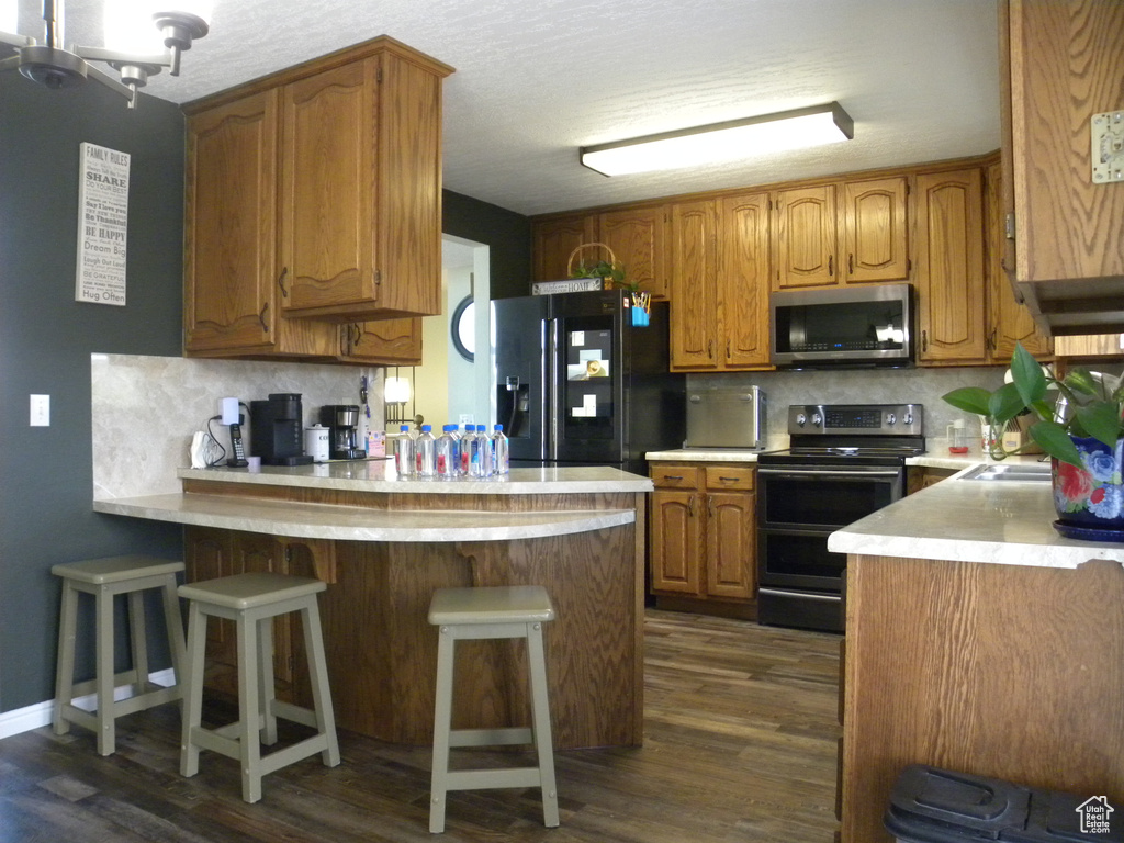 Kitchen featuring stainless steel appliances, a peninsula, decorative backsplash, and light countertops