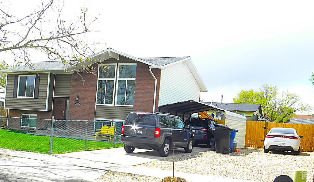 View of side of home with brick siding, a fenced front yard, and concrete driveway
