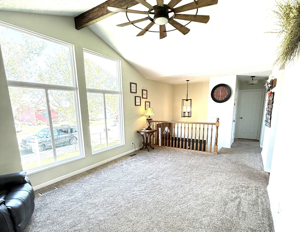 Carpeted spare room with ceiling fan and baseboards