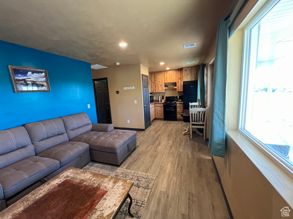 Living area with visible vents, baseboards, a healthy amount of sunlight, and light wood-type flooring