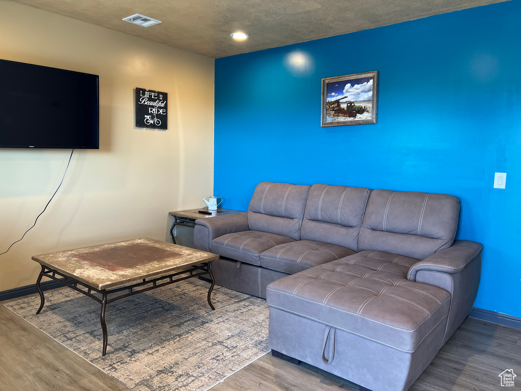 Living room with wood finished floors, recessed lighting, visible vents, and baseboards