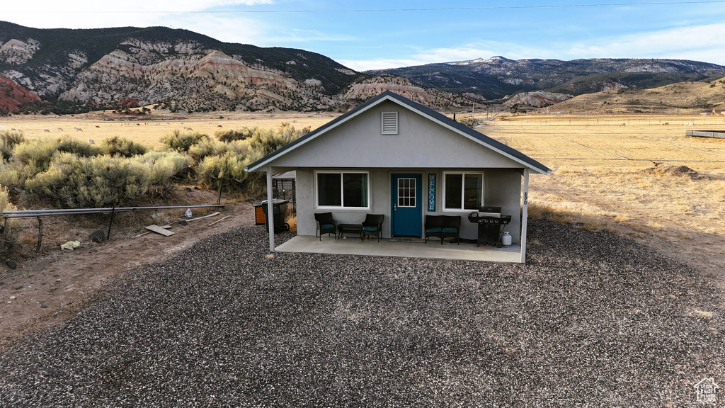 Back of property with a porch, a mountain view, and stucco siding