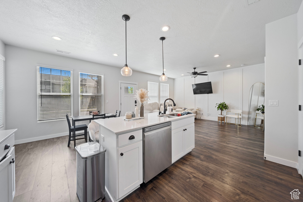 Kitchen featuring dark wood finished floors, stainless steel dishwasher, light countertops, a sink, and a ceiling fan
