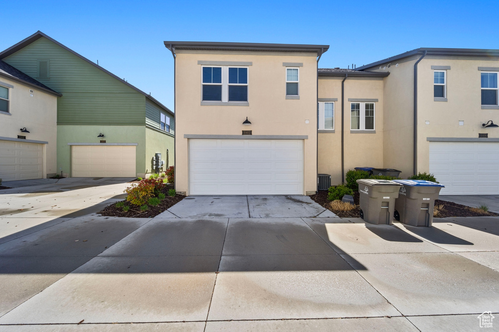 View of property with stucco siding, driveway, and an attached garage