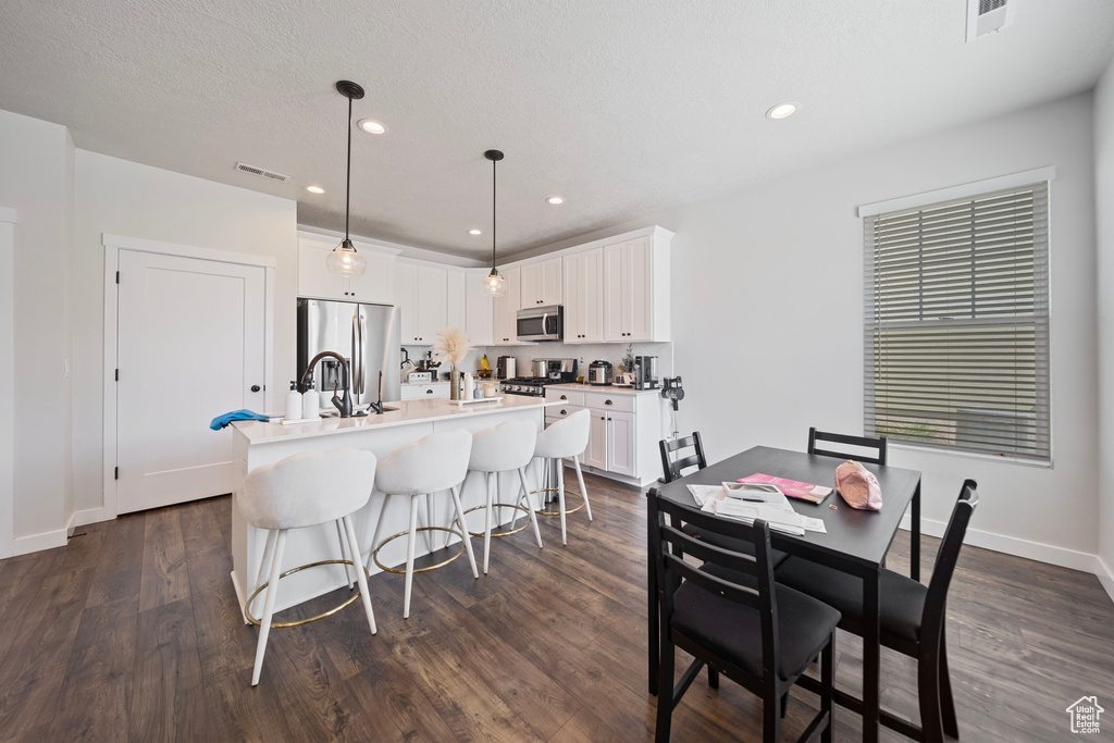 Dining space featuring dark wood-style floors, visible vents, baseboards, and recessed lighting