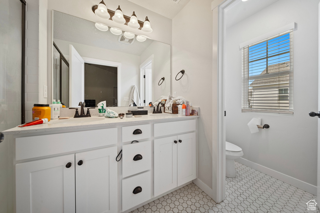 Bathroom with toilet, a sink, double vanity, and baseboards