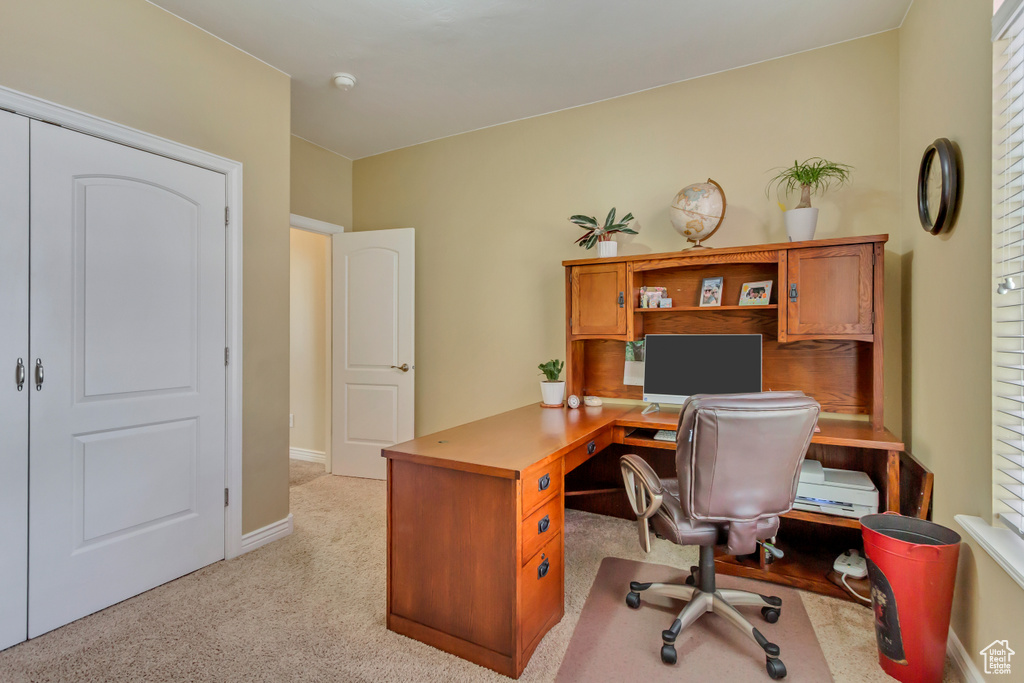Office space with baseboards and light carpet
