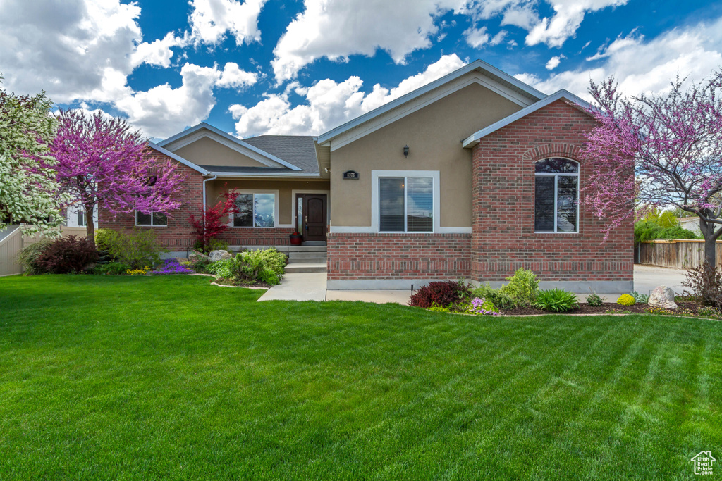 Ranch-style house featuring brick siding, fence, stucco siding, and a front yard