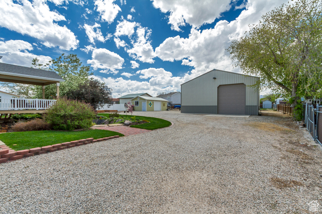 Exterior space featuring driveway, an outdoor structure, a residential view, a detached garage, and fence