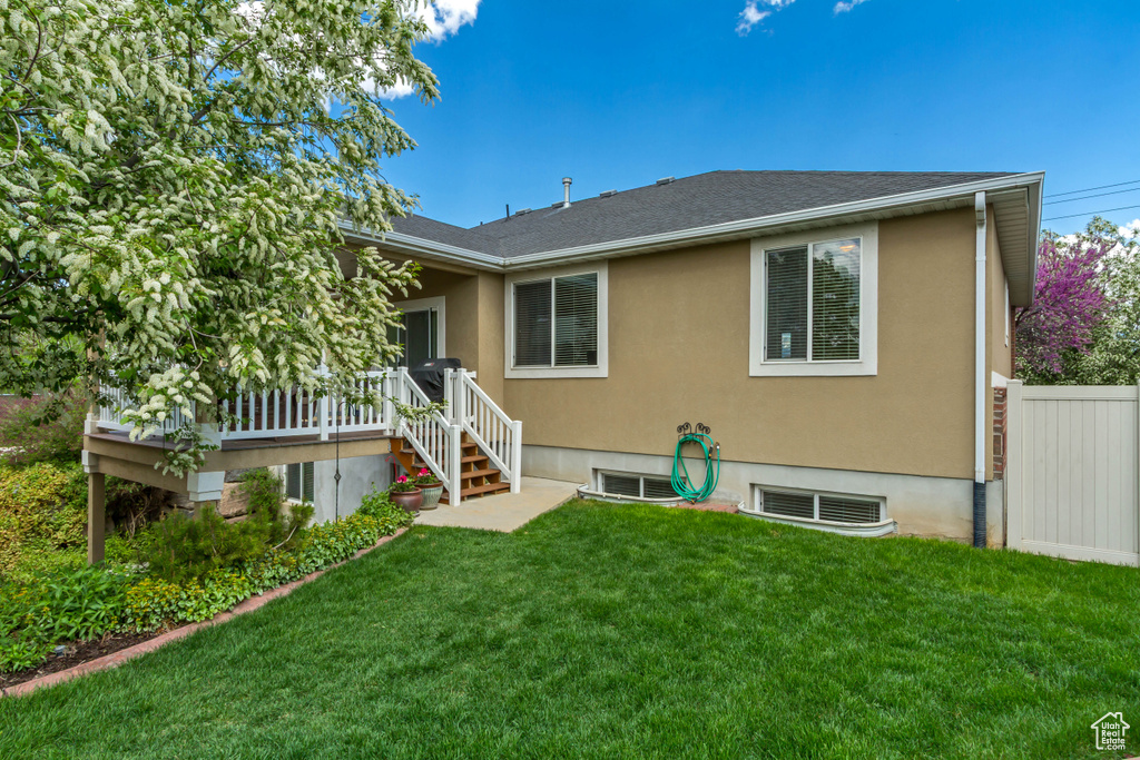 Rear view of house with a deck, a yard, and fence