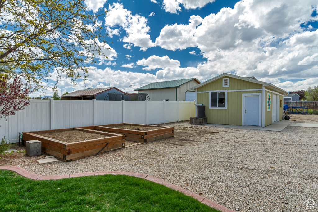 View of yard featuring an outdoor structure, a garden, and a fenced backyard