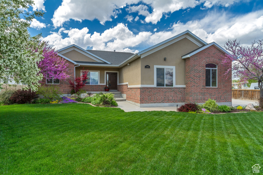 Ranch-style home with brick siding, stucco siding, and a front yard